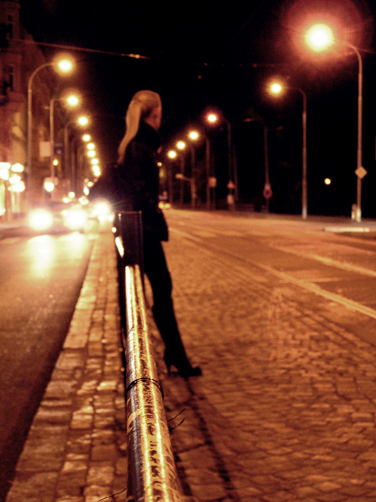 Young Woman Waiting for a Tram at Night